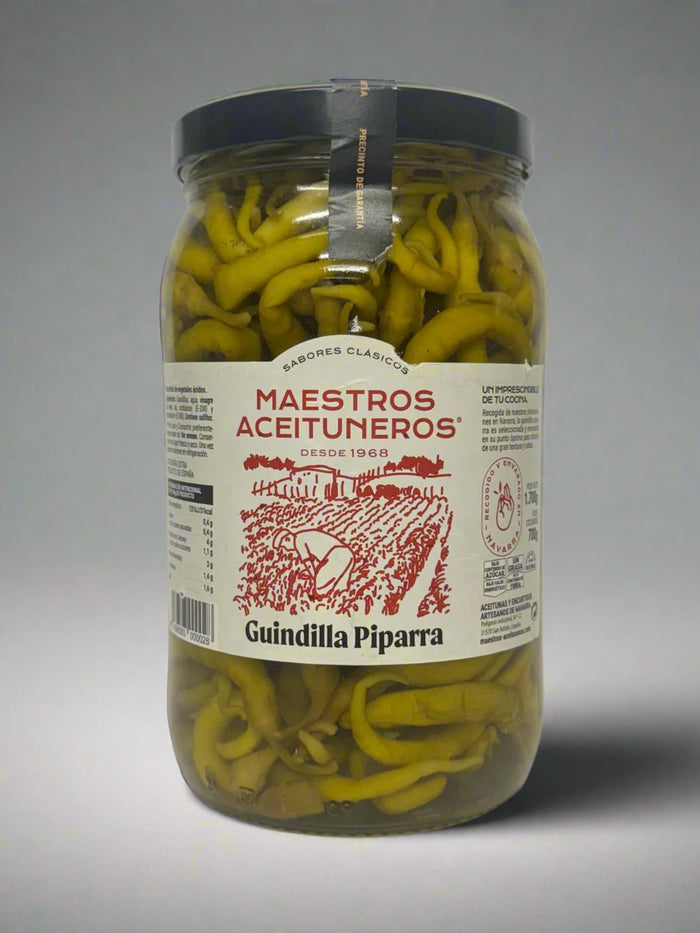 Jar of pickled green peppers with 'Maestros Aceituneros' label on a white background