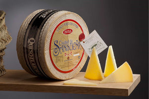 Round cheese wheel with a label on a wooden board against a dark background