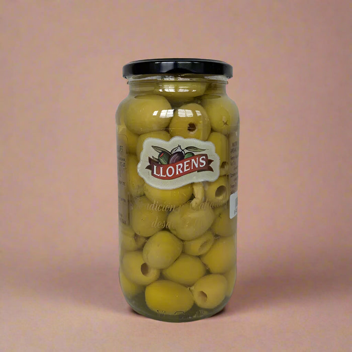 Jar of Llorens olives on a textured surface with a light background