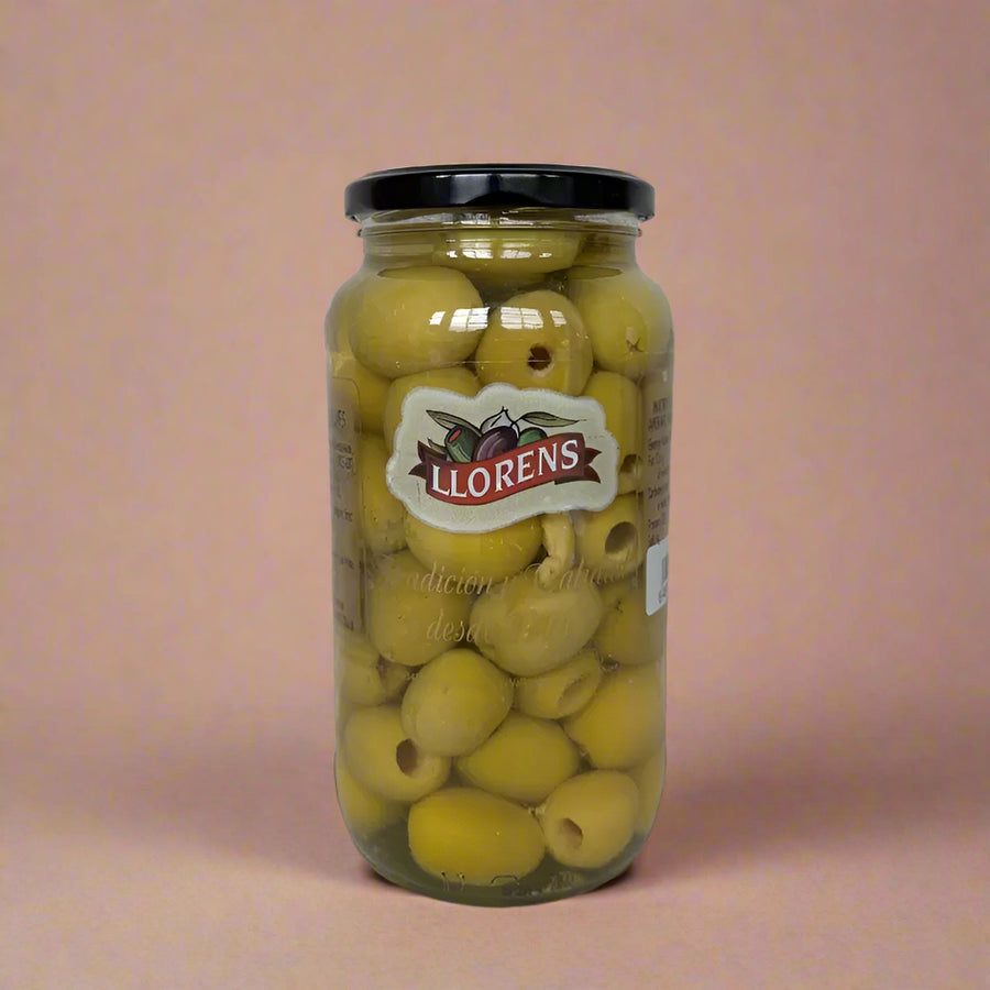 Jar of Llorens olives on a textured surface with a light background